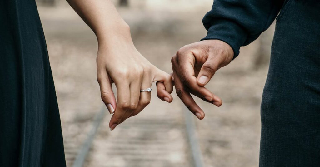 A romantic couple holding hands, symbolizing love and unity on a scenic railtrack.