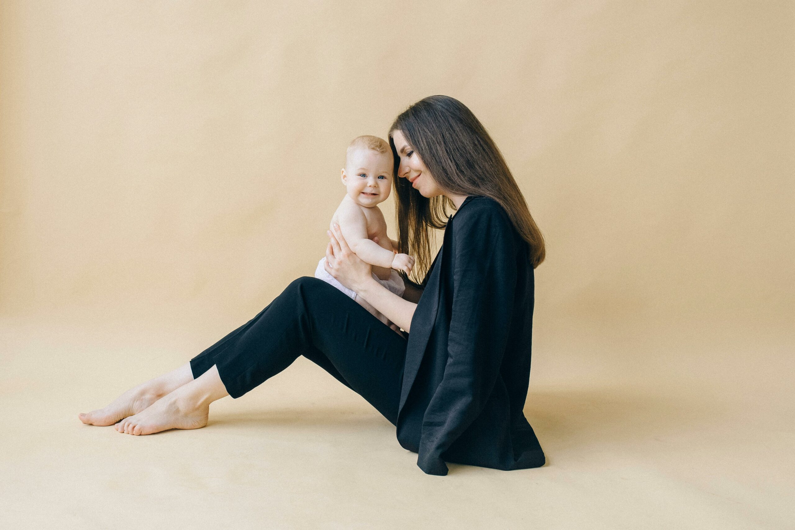 A loving moment captured between a mother and her baby in a studio setting.