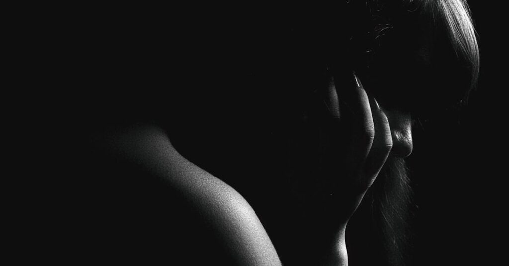 Dramatic black and white silhouette of a woman in deep thought.