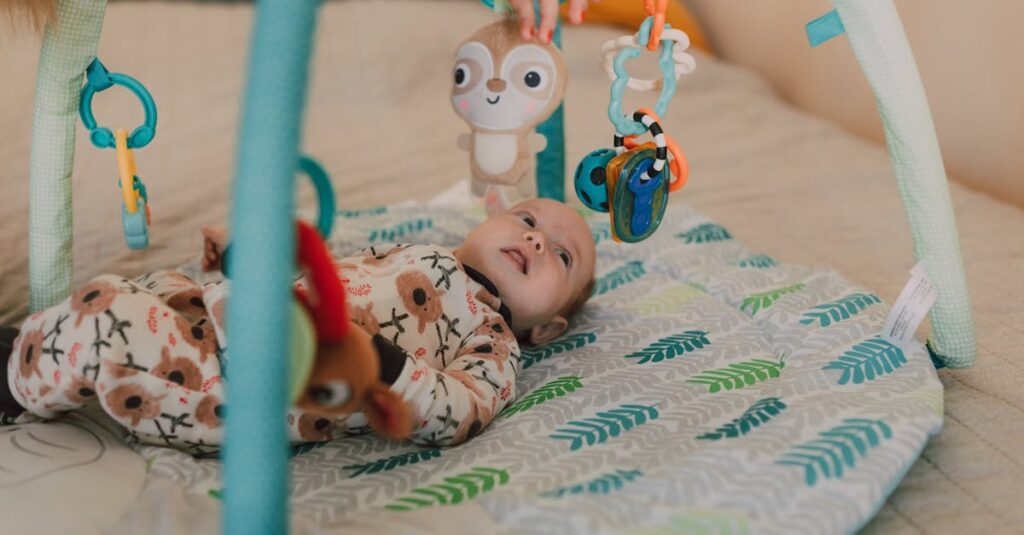 Cute baby lying on a play mat wearing a onesie and interacting with hanging toys.