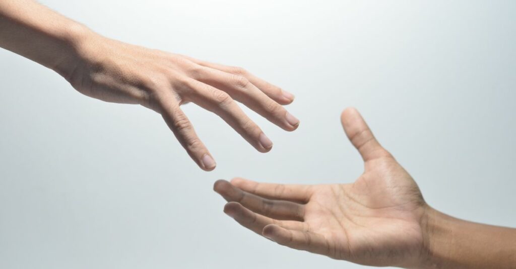 Close-up of two hands reaching towards each other on a neutral background, symbolizing connection.