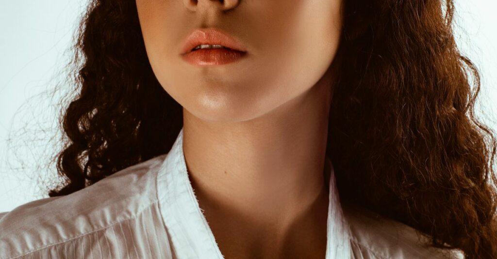Portrait of a woman with curly hair wearing sunglasses and a white shirt.